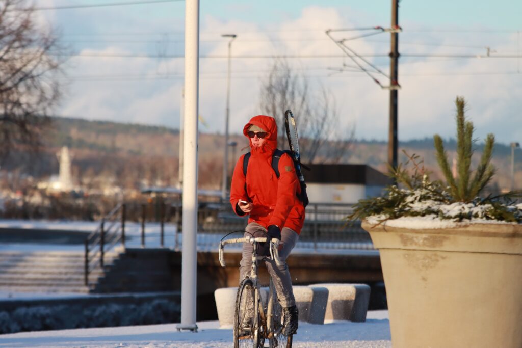 Homme bien couvert avec une veste, un bonnet et des gants en vélo 